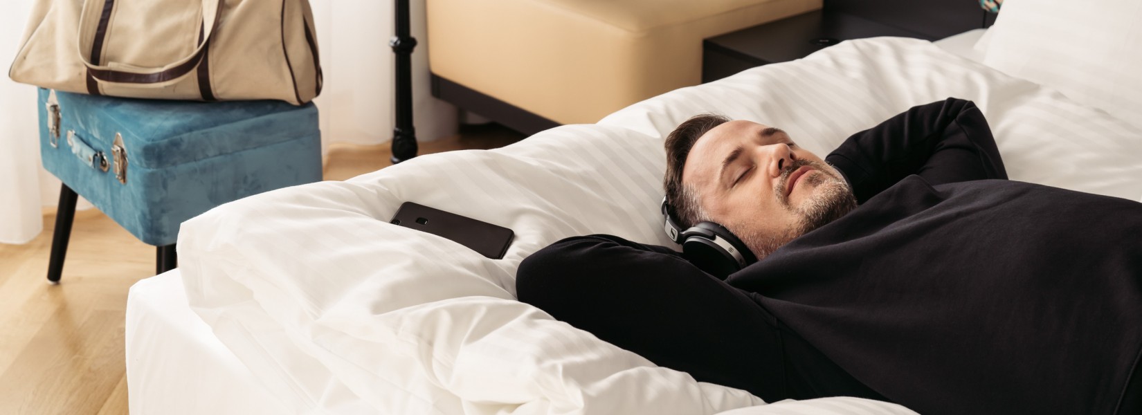 Man in bed with headphones in hotel Schani Salon 