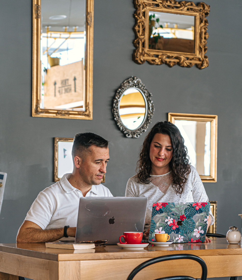 Zwei Personen sitzen mit ihren Laptops an einem Tisch