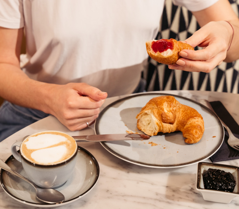 Croissant mit Marmelade auf einem Teller neben einem Kaffee