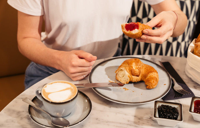 Eine Tasse Kaffe neben einem Teller mit einem Croissant