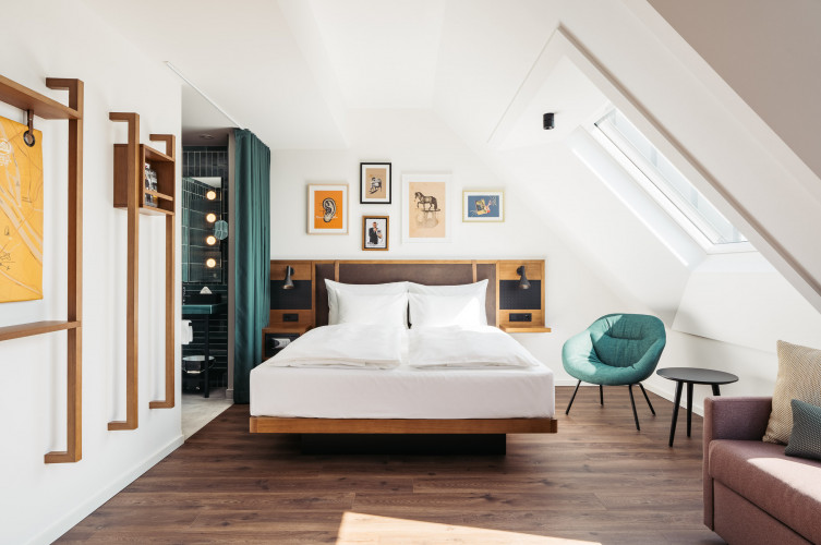 Ein modern eingerichtetes Schlafzimmer mit Dachschräge und offenen Bad im Hotel Schani